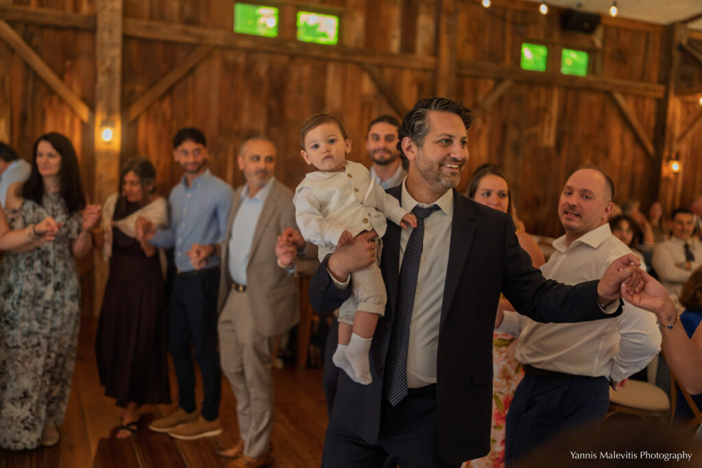 Two men dance through the reception while carrying young children.