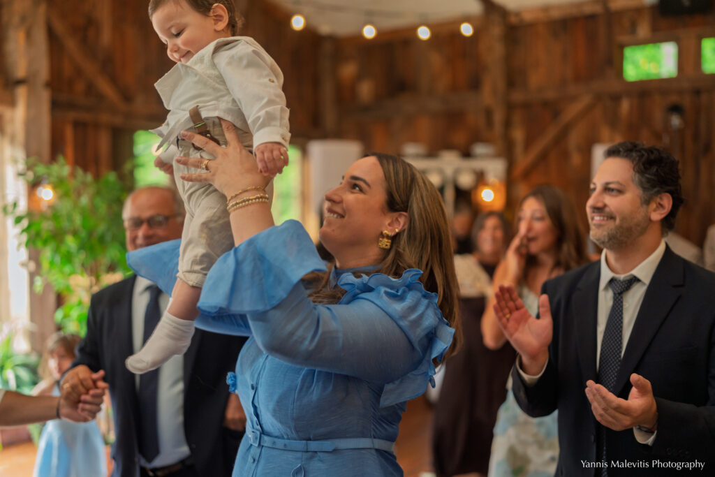 A woman lifts the newly baptized child as family members applaud.
