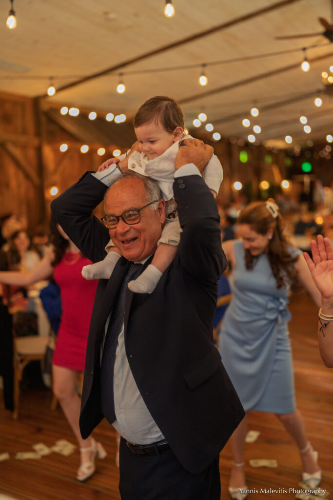 A grandfather dances with the newly baptized child on his shoulders.