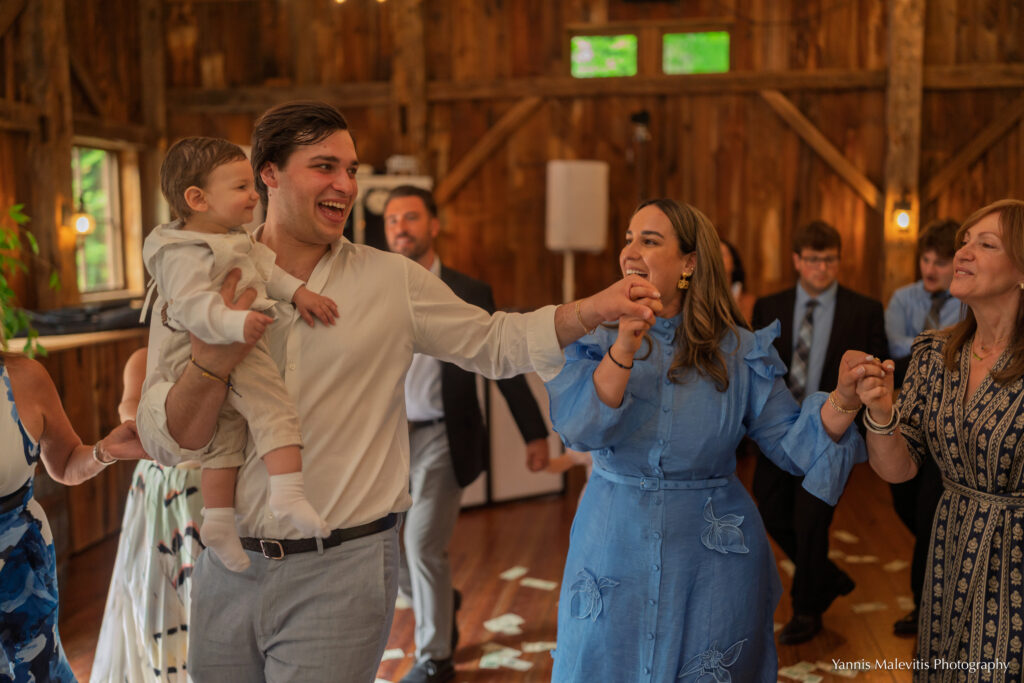 A man carries a young boy while dancing hand in hand with family members.