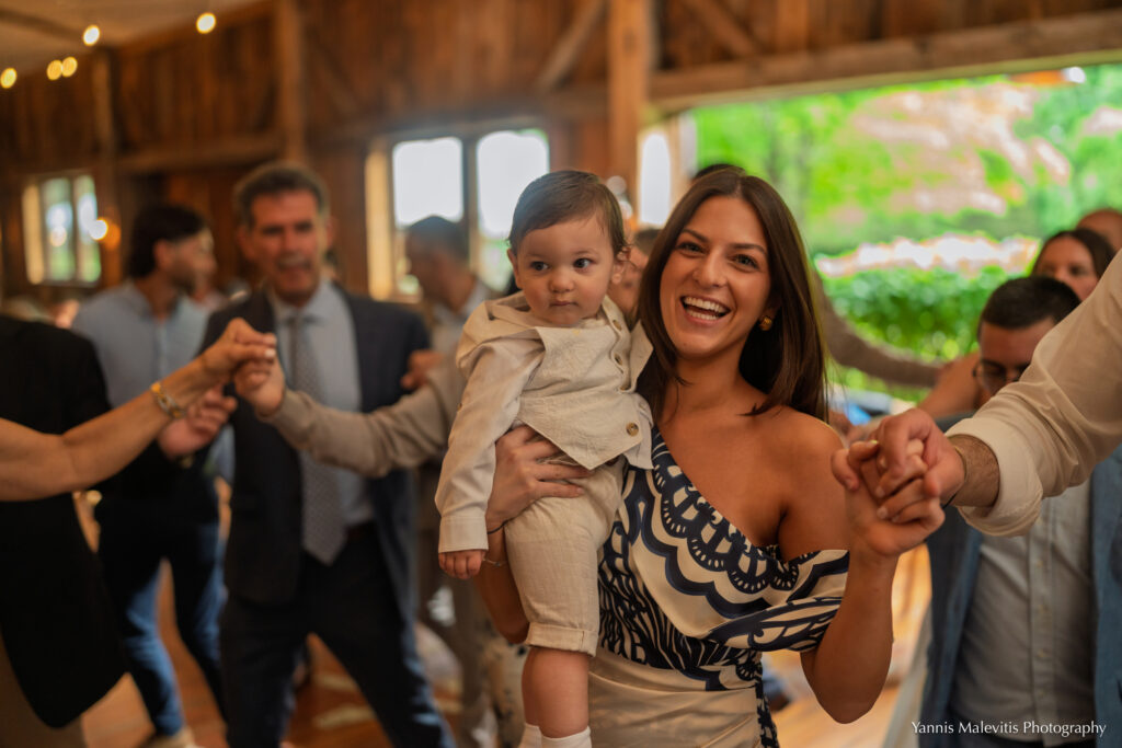 A woman carries a young boy while joining the family dance circle.