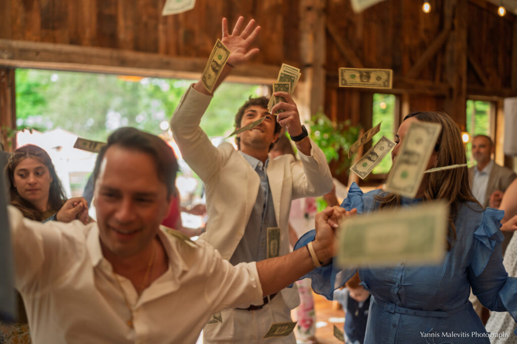 A guest tosses dollar bills above the dancers during the traditional money dance.