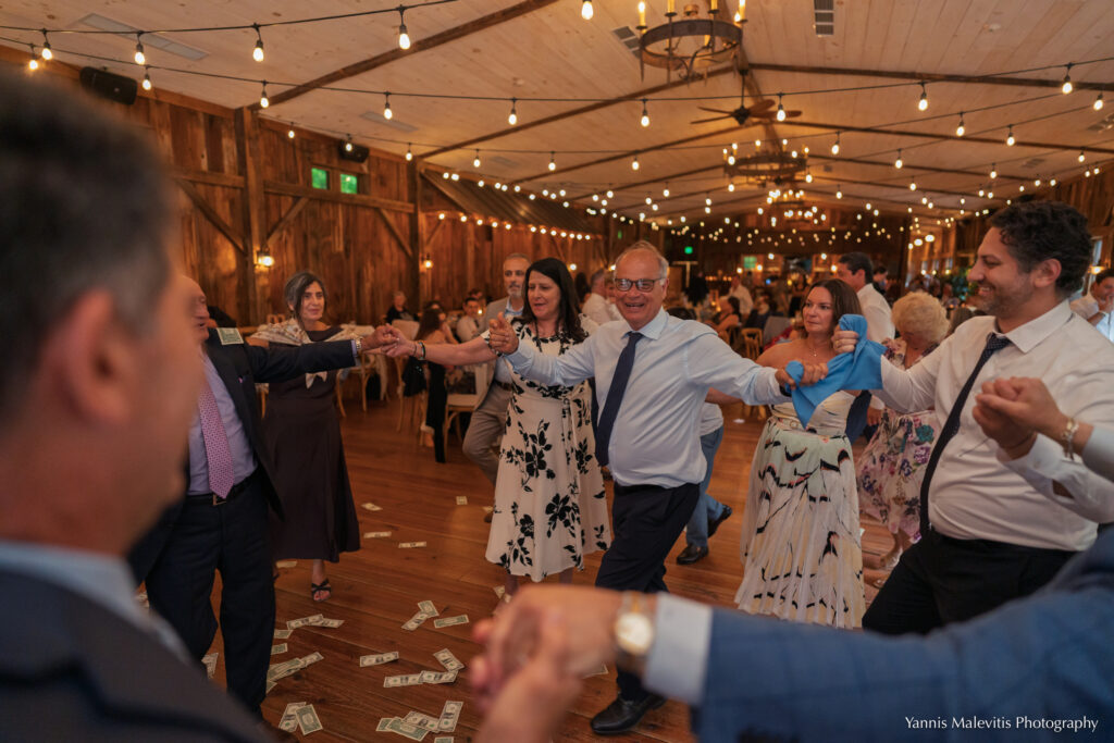 Guests join hands in a Greek dance as money covers the reception floor.
