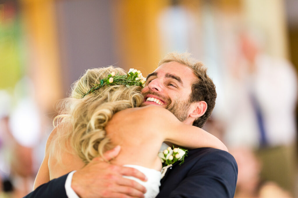 Smiling groom embraces his bride during their wedding celebration.