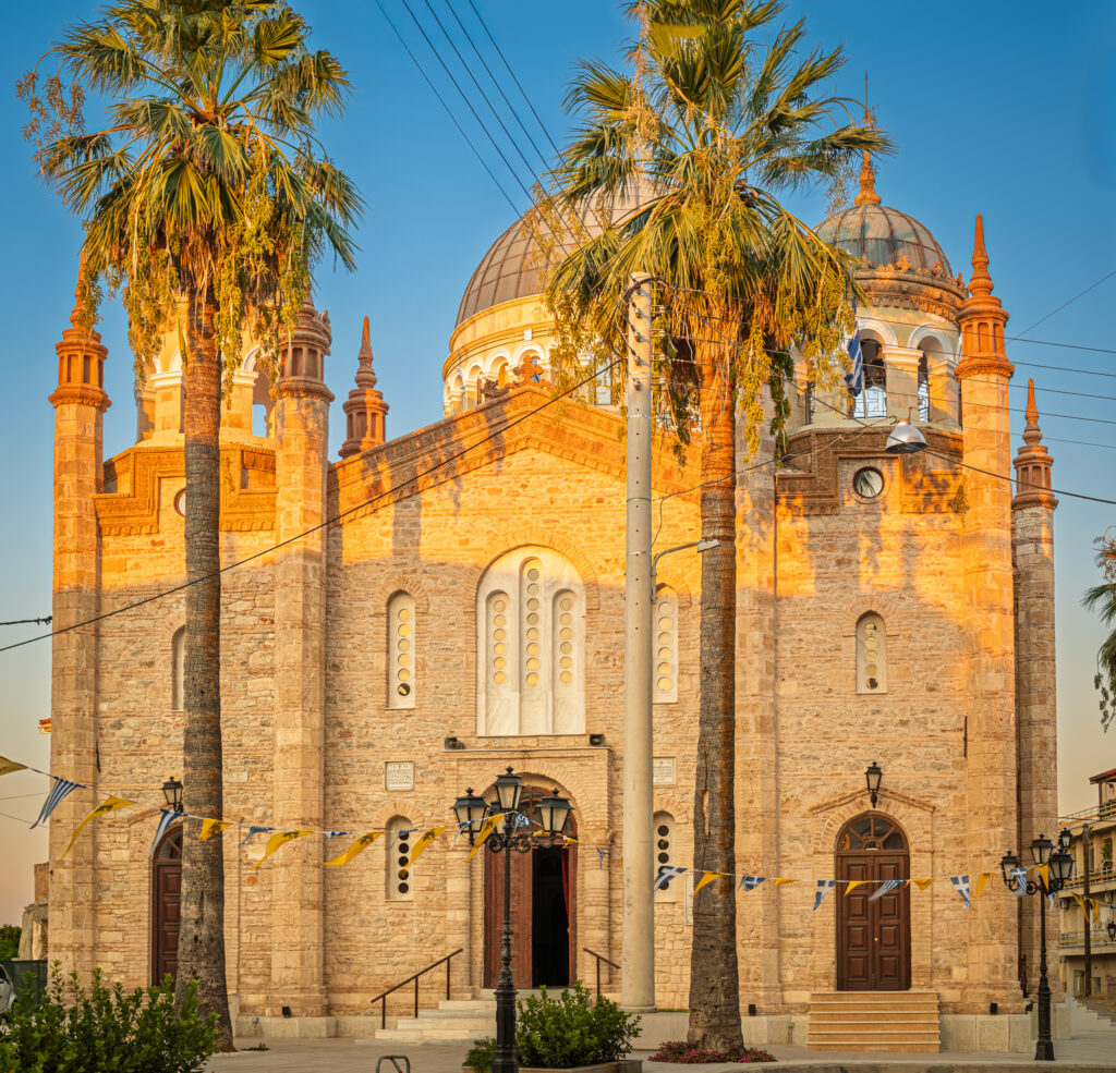Warm late-evening view of the principal façade, framed by the palm trees