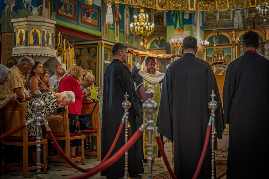 A priest carries an embroidered Dormition cloth through worshippers at Panagia Faneromeni.
