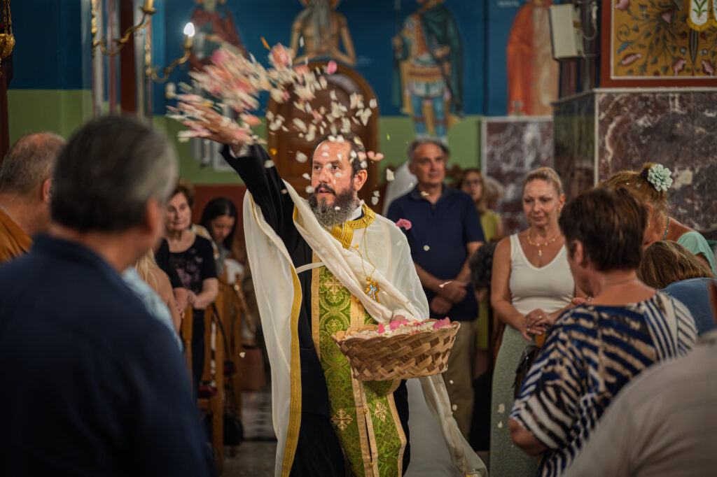 A priest scatters flower petals before the gathered congregation.